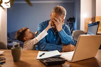 
		Ein gestresster Vater sitzt am Laptop mit seinem Sohn
	